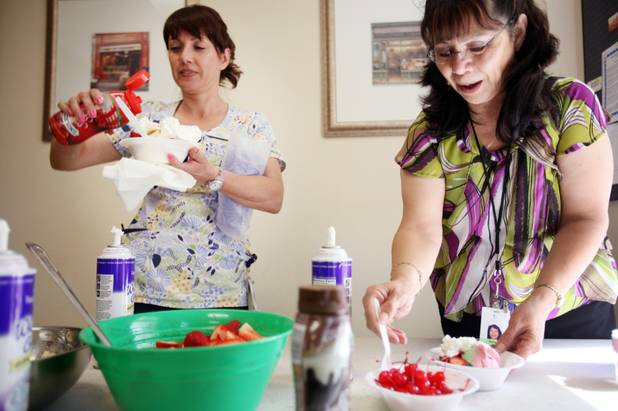 Medical assistant Dee Iniesta, left, and financial counselor Sandy Turkington add toppings to their ice cream during a company ice cream party at Comprehensive Cancer Centers of Nevada in Las Vegas on Monday, April 30, 2012.