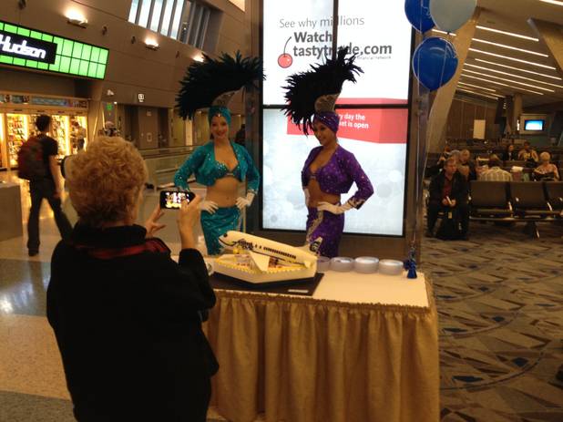 Marilyn Romano, regional vice president of Alaska for Alaska Airlines, takes a cellphone photo of a cake celebrating the inaugural flight from Anchorage, Alaska, to Las Vegas, at a Terminal 3 gate at McCarran International Airport on Dec. 19, 2013.