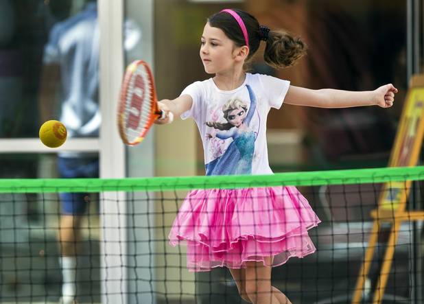 Sydney Dockendorf, 6, returns a ball as instructor J.C. Pauli watches during a United States Tennis Association youth clinic at Macy’s court in Summerlin. 
