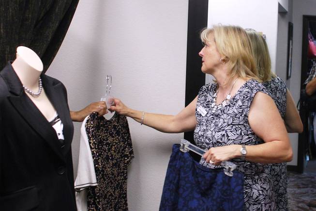 Theresa Anderson hands Sonji McTear some additional blouses to try on at Dress for Success Saturday, May 31, 2014.