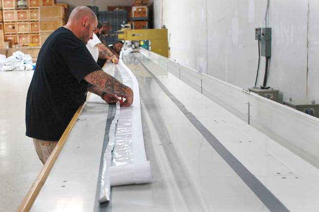 Technicians trim a piece of fabric on a seam welder at Creative Tent International July 30, 2014.