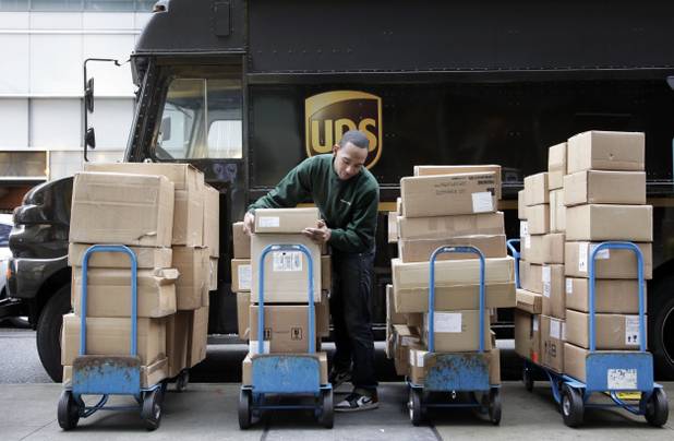A United Parcel Service driver unloads packages from a truck and arranges them for delivery in New York. 